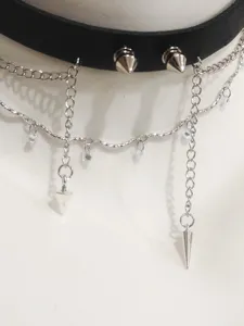 Close-up detail of punk gothic black leather choker necklace with metal spikes and silver chains.
