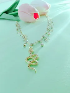 Detailed close-up of the double-layer rhinestone snake pendant anklet on a green background.