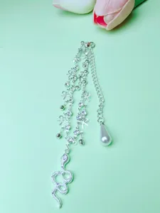 Close-up detail of silver multi-layer anklet featuring snake pendant and rhinestone bows.