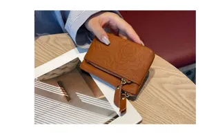 Detail view of brown leather coin purse with embossed floral pattern and zipper closure.