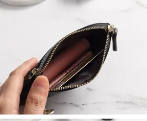Close-up detail of black leather mini coin purse showing interior zip compartment and slots.