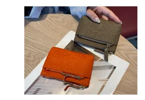 Close-up of genuine leather embossed coin purse with floral pattern and secure zipper closure.