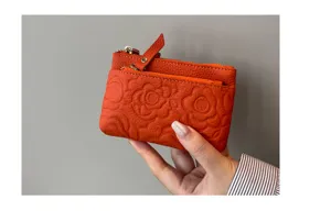 Orange leather coin purse detail, embossed floral pattern, compact zip card wallet.