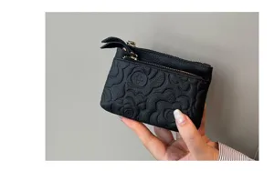 Black leather coin purse compact card holder with debossed floral pattern and zippers.