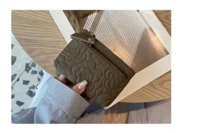 Leather coin purse detail showing embossed camellia flower pattern and secure zipper closure.