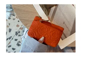 Close-up detail view of the genuine leather coin purse featuring elegant embossed flower patterns.