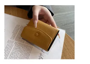Vue détaillée du porte-cartes en cuir jaune avec bouton-pression et texture élégante.