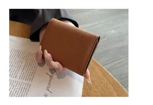 Vue détaillée du porte-cartes marron en cuir grainé sur un élégant bureau en bois.