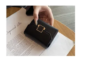 Gros plan détaillé sur un porte-cartes en cuir noir compact doté d'un fermoir en métal doré.