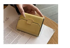 Gros plan détaillé du porte-cartes compact en cuir jaune avec fermoir métallique élégant.