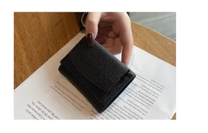 Detailed view of a compact black genuine leather trifold wallet with pebble texture and coin pocket.