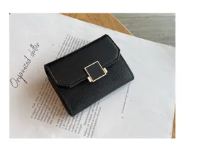 Détail du porte-cartes en cuir noir, portefeuille compact avec fermoir carré doré élégant.