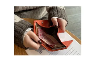 Detailed view of the orange leather mini wallet featuring card slots and coin pocket.