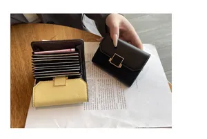 Porte-cartes en cuir compact doté de plusieurs fentes, boucle métallique et design élégant.