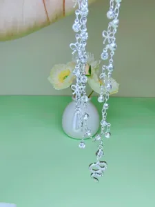 Detailed view of silver double-layer anklet with snake pendant, rhinestones and cute bows.