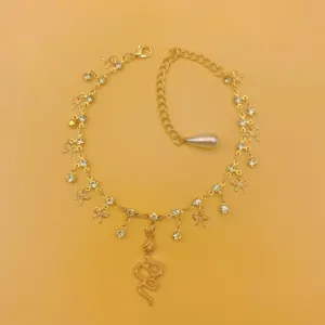 Exquisite rhinestone bow and snake pendant gold anklet, sparkling fashion jewelry detail.