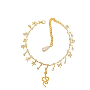 Gold snake pendant anklet with sparkling rhinestones and cute bow charms for women.