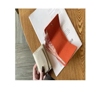 Close up view of minimalist short leather wallets in beige and orange with card slots.