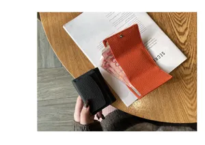 Detailed shot of minimalist leather trifold wallet on wooden table with cash inside.