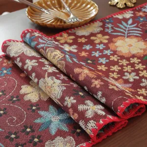 Primo piano dettagliato del runner da tavola jacquard retrò con motivo floreale e bordo rosso.