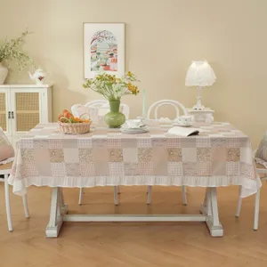 Detailed view of pastoral cotton patchwork tablecloth with cute ruffled hem for dining table decor.