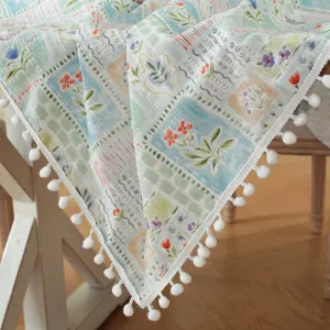 Pastoral cotton jacquard tablecloth detail, fresh floral pattern with white pom-pom fringe hem.