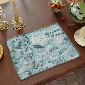 Primo piano dettaglio della tovaglietta jacquard floreale blu con bordi conchiglia decorativi.