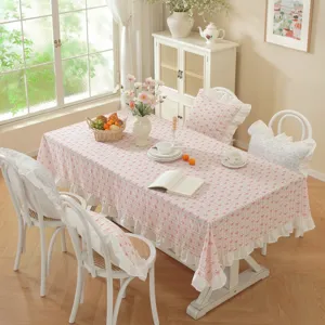 Pastoral pink floral print tablecloth scene with delicate ruffle trim and cozy chair cushions.