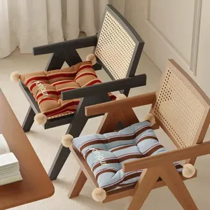 Retro gestreiftes Sitzkissen mit Pompons und Rattansessel Detail in gemütlicher Raumkulisse