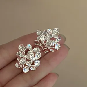 Close-up detail shot of exquisite multi-petal metallic flower stud earrings, elegant texture.