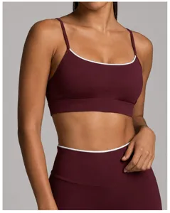 Gros plan détaillé de la soutien-gorge de sport bordeaux avec passepoil blanc et pantalon.
