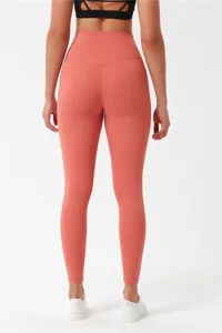 Back detail view of women high waist peach lift brushed yoga leggings in coral pink color.