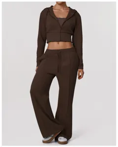 Détail d'un sweat à capuche court zippé marron et d'un pantalon de sport large.