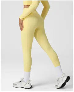 Detail view of yellow high-waist yoga leggings and long sleeve crop top with side pockets.