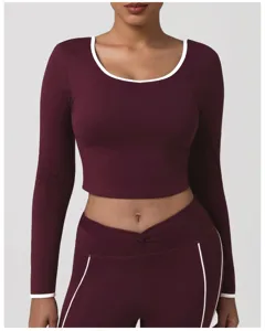 Primo piano di un top corto a maniche lunghe bordeaux con finiture a contrasto bianche per yoga.