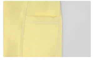 Detail view of yellow yoga pants side pocket, high-waisted stretchy fitness activewear fabric.