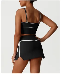 Back detail view of women athletic crop top and matching skirt set with white piping trim.