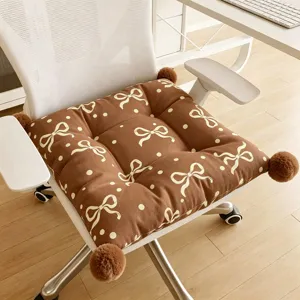 Brown bow seat cushion detail, cozy chair pad with polka dots and fluffy pom-pom corners.