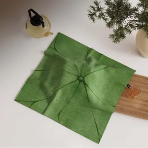 Vista detallada de una tela cuadrada verde de cubierta contra polvo para juego de té.