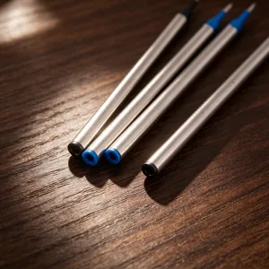 Detalle macro de repuestos de bolígrafo metálicos de calidad sobre fondo de madera veteada