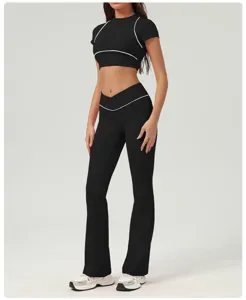 Vista dettagliata del crop top sportivo nero e dei pantaloni da yoga svasati con profilo bianco.