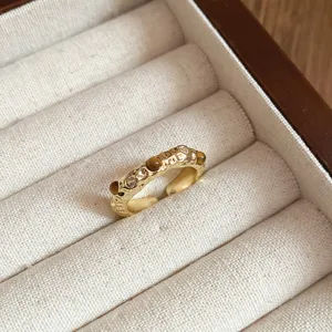 Detaillierte Nahaufnahme eines unregelmäßigen Vintage-Goldrings mit Tigerauge und Zirkonen.