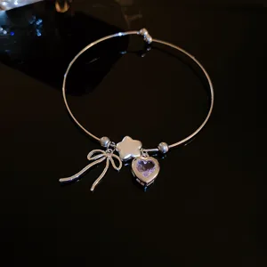 Detail shot of silver tone bracelet featuring cute bow star and purple heart charms.