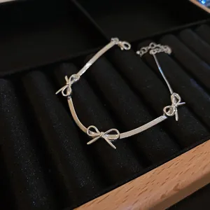 Silver tone snake chain bracelet featuring three delicate bowknot charms closeup detail shot.