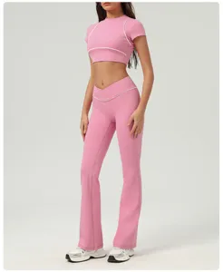 Set crop top sportivo rosa e pantaloni yoga svasati con dettagli di piping bianco.