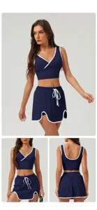 Navy blue athletic two-piece set, sleeveless crop top and drawstring skirt for fitness.