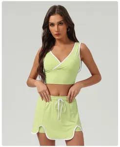 Close-up detail of the light green athletic crop top and matching shorts skirt set with white trim.