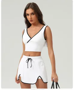 Close-up detail of white activewear crop top with black trim and sports skirt set.