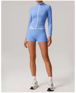 Close-up detail of the blue athletic zip-up top and high-waist yoga shorts with white piping.