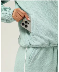 Close-up detail of women light green textured athletic jacket pocket and soft fabric.